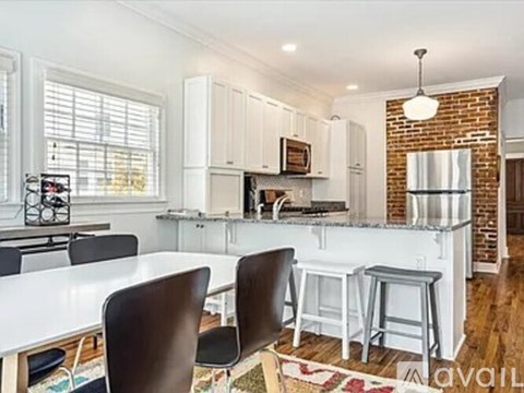 A kitchen with white cabinets and a brick wall.