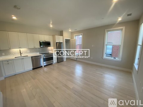 A spacious kitchen with white cabinets and a wooden floor.
