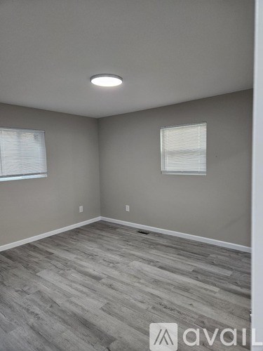 A room with a wooden floor and two windows.