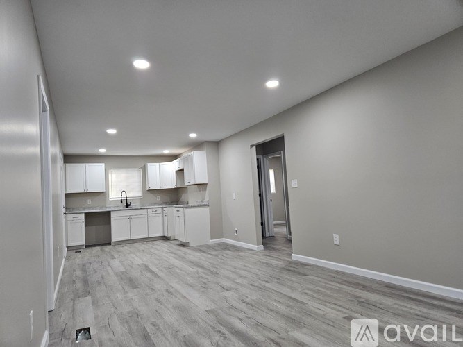 A spacious kitchen with white cabinets and a grey floor.