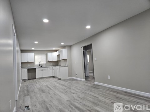 A spacious kitchen with white cabinets and a grey floor.