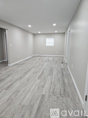 A spacious room with wooden flooring and a window.