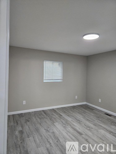 A room with a window and wooden flooring.
