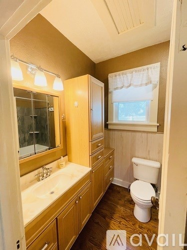 A bathroom with a toilet, sink, and mirror.