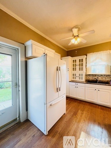 A kitchen with a white refrigerator and wooden floors.