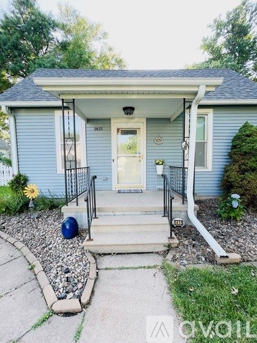 A blue house with a white door and a black railing on the steps.