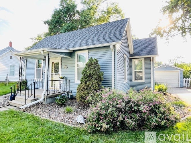A house with a blue siding and a grey roof with a small front porch.