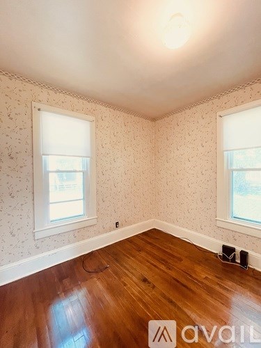 A room with wooden floors and two windows.