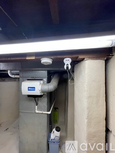 A white smoke detector is mounted on a wall above a grey electrical box.