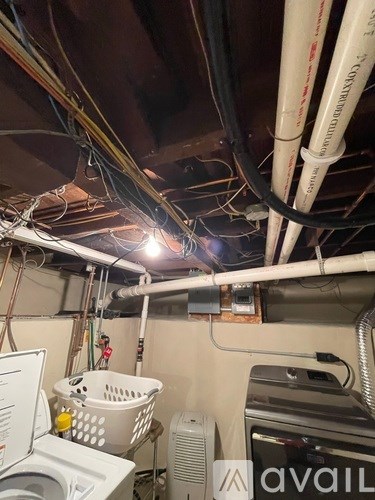 A laundry basket sits on a washer and dryer in a small, cluttered room.