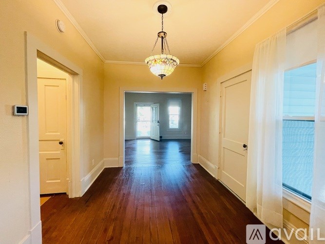 A hallway with a chandelier and a door on the left.