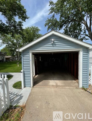 A blue garage with a white fence in front.