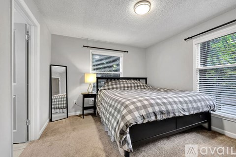 A bedroom with a bed, nightstand, and window.