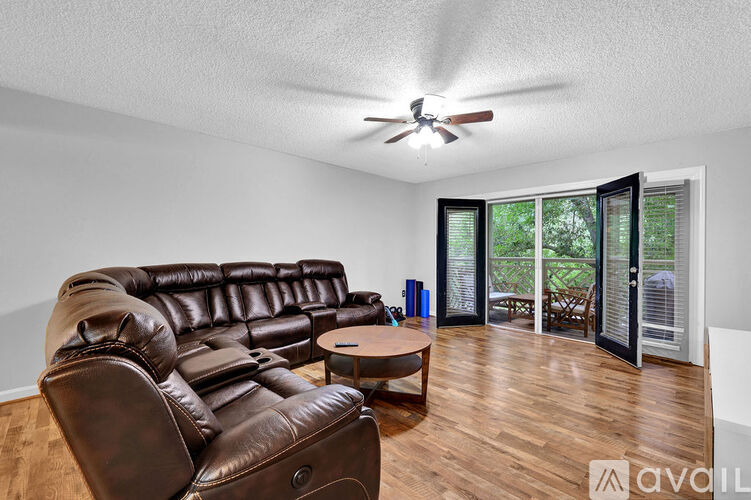 A living room with a brown leather couch and a ceiling fan.