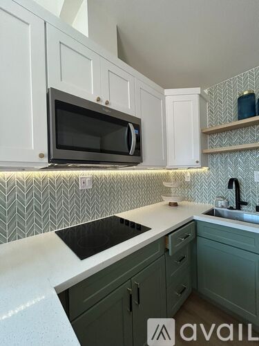 A kitchen with a black microwave above a black countertop.