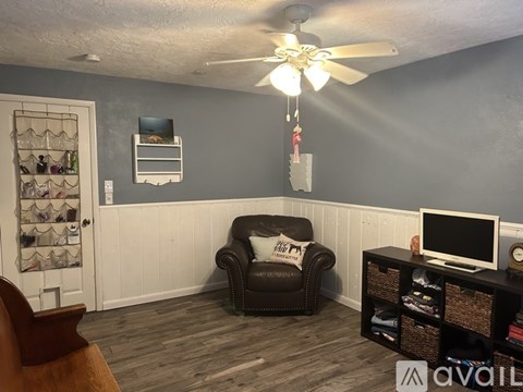 A living room with a black leather chair and a ceiling fan.