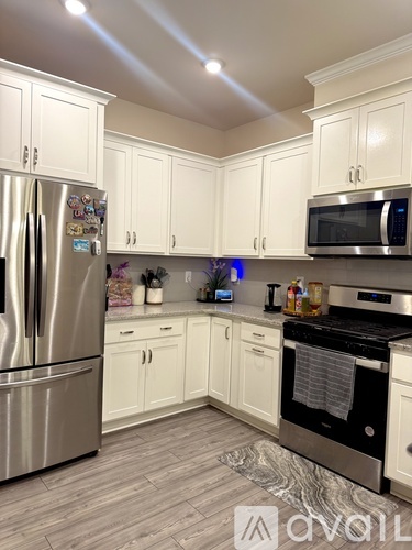 A kitchen with white cabinets and a stainless steel refrigerator.