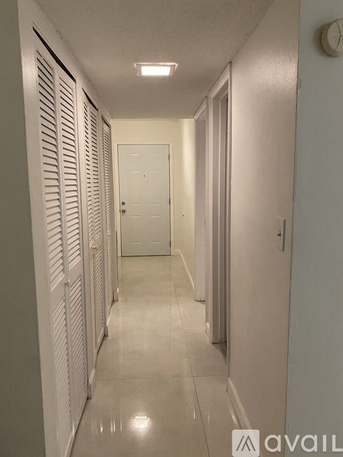 A long hallway with white doors and a tiled floor.