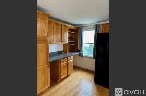 A kitchen with wooden cabinets and a black refrigerator.