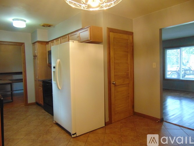 A white refrigerator in a kitchen with wooden cabinets and a door.