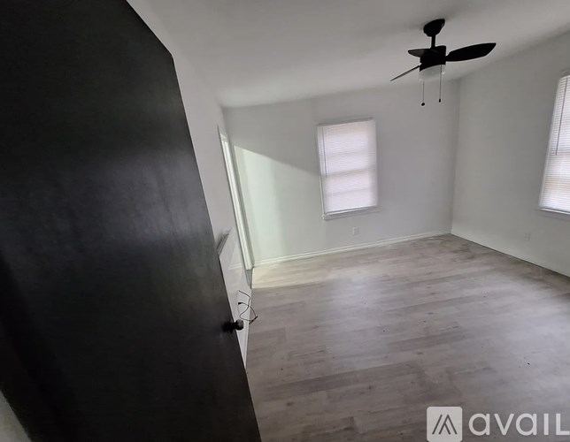 A room with a ceiling fan and two windows.