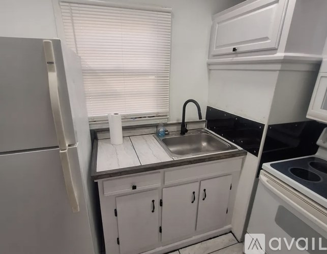 A kitchen with a refrigerator, sink, and stove.