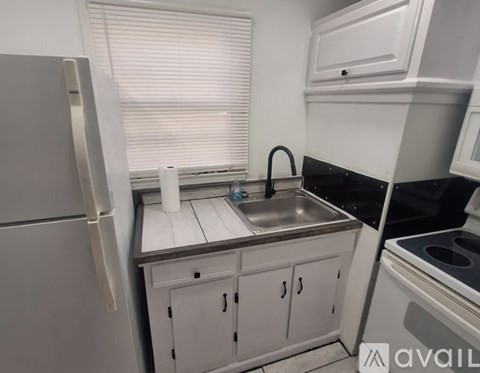 A kitchen with a refrigerator, sink, and stove.