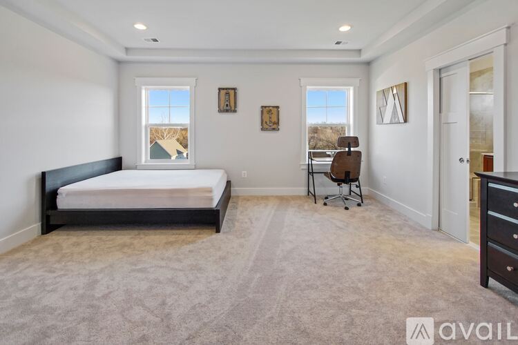 A bedroom with a large bed and a chair by the window.