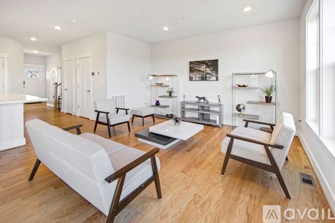 A living room with white furniture and a wooden floor.