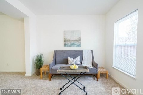 A living room with a grey couch and a painting on the wall.
