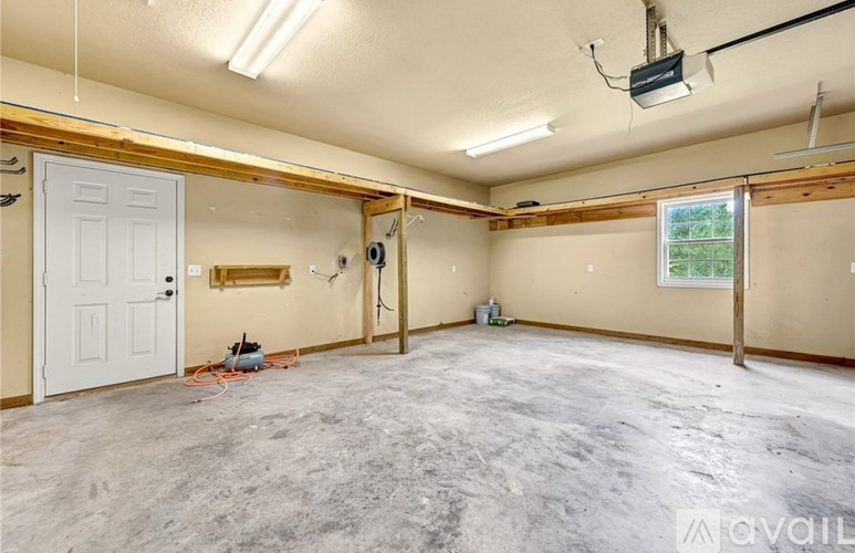 A room with a white door and a window with a view of trees outside.