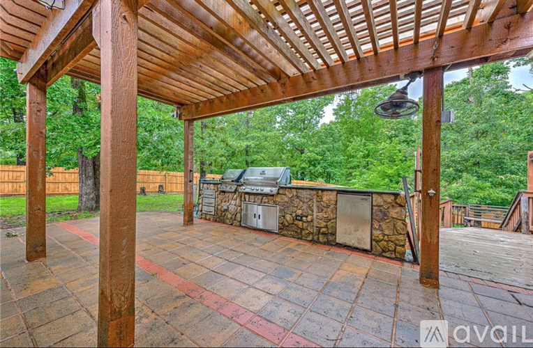 A wooden pergola with a stone wall and a hot tub underneath it.