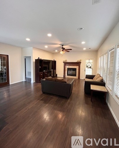 A spacious living room with dark wood flooring and furniture.