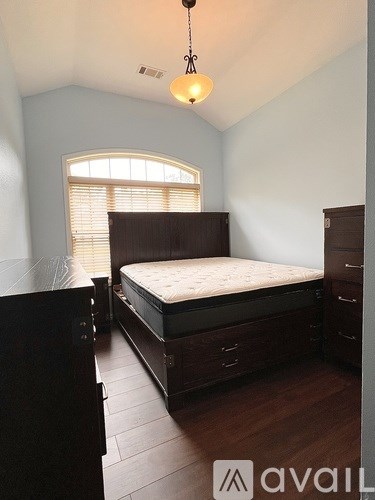 A bedroom with a bed, dresser, and window.