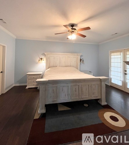 A bedroom with a bed, dresser, and ceiling fan.