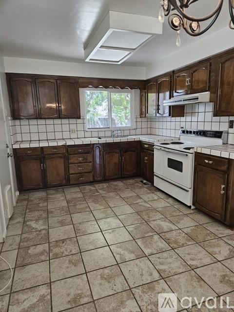 A kitchen with brown cabinets and a white stove top oven.