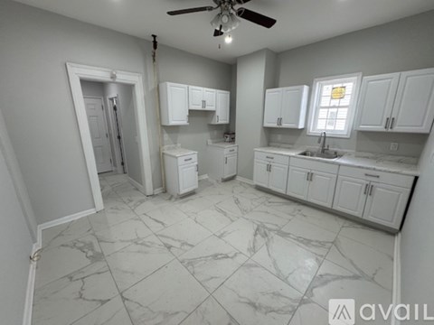 A kitchen with white cabinets and marble flooring.