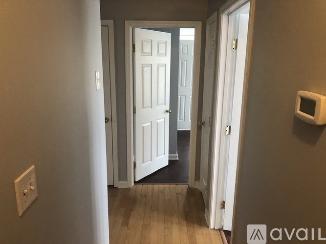 A hallway with a white door and a wall-mounted device on the wall.