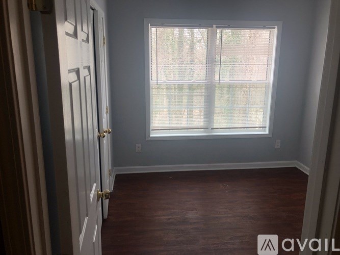 A room with a wooden floor and a window with blinds.