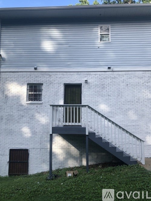 A white building with a grey roof and a balcony with stairs.
