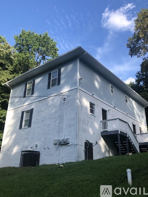 A white two-story house with a balcony on the second floor.