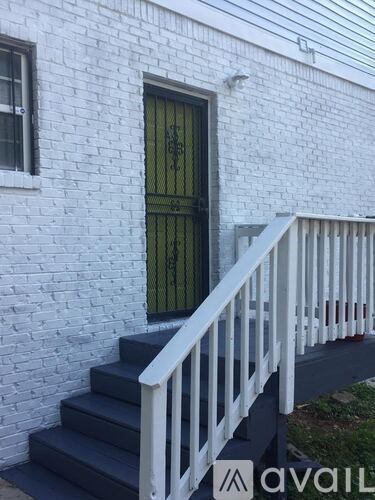 A white brick building with a green door and a white railing.