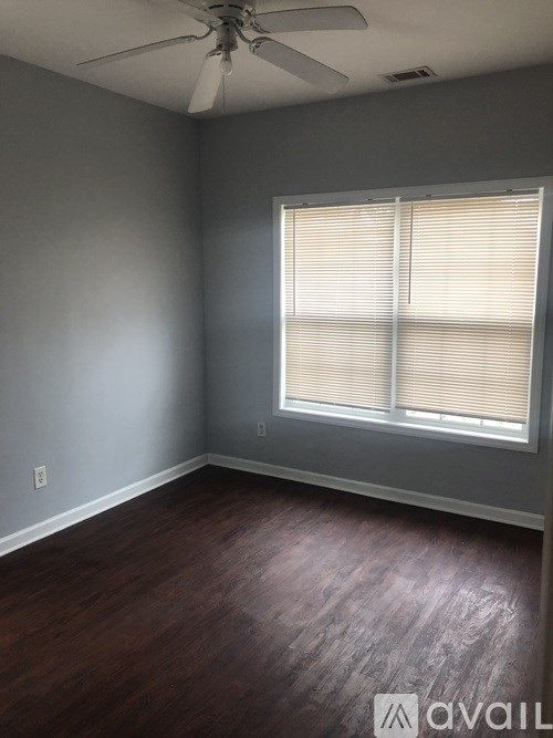 A room with a ceiling fan and wooden flooring.