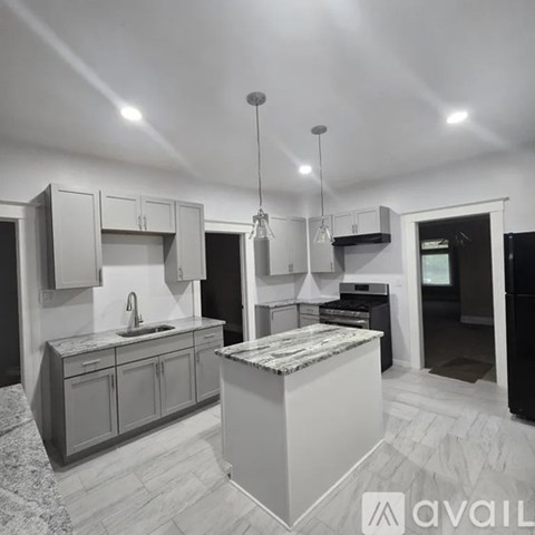 A modern kitchen with a marble island and pendant lights.