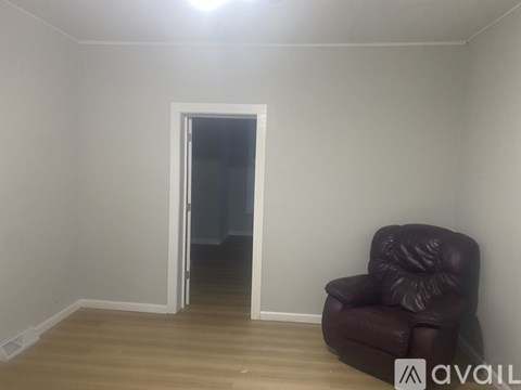 A brown leather chair is placed in a room with a doorway.