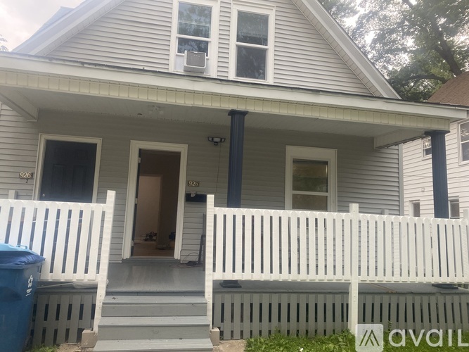 A house with a white porch and a blue trash can.