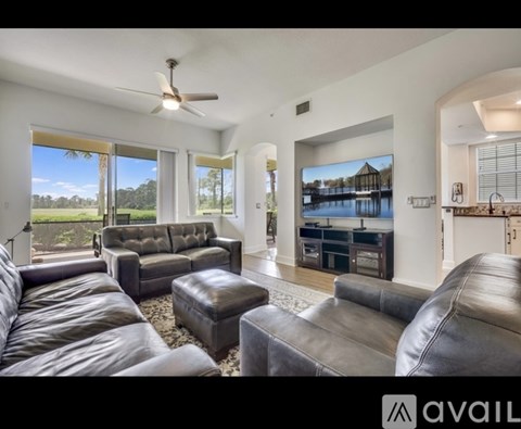 A living room with a large leather couch and a flat screen TV mounted on the wall.