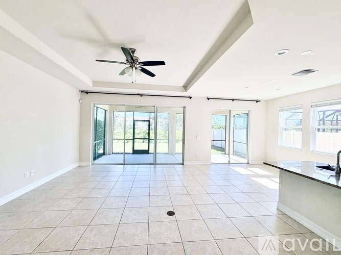 A spacious room with a ceiling fan and sliding glass doors.