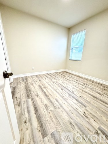 A room with wooden flooring and a window with blinds.