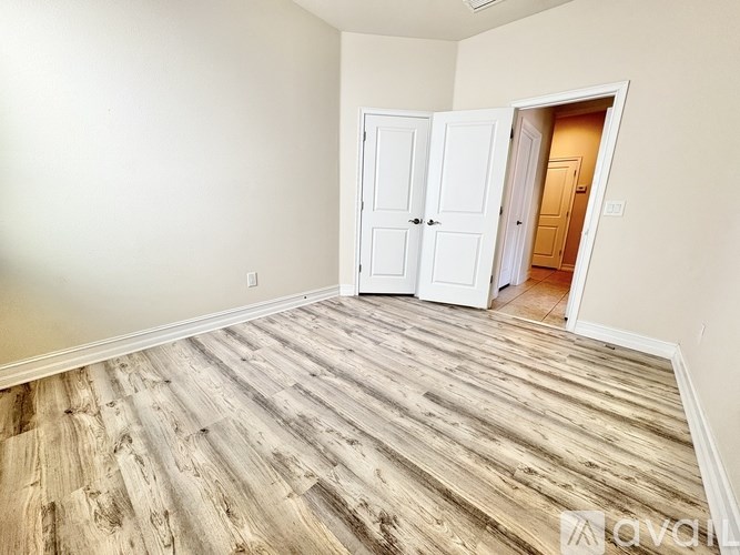 A room with a white door and a wooden floor.